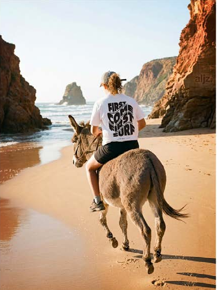 Riding a donkey down the beach in an aljzr tee